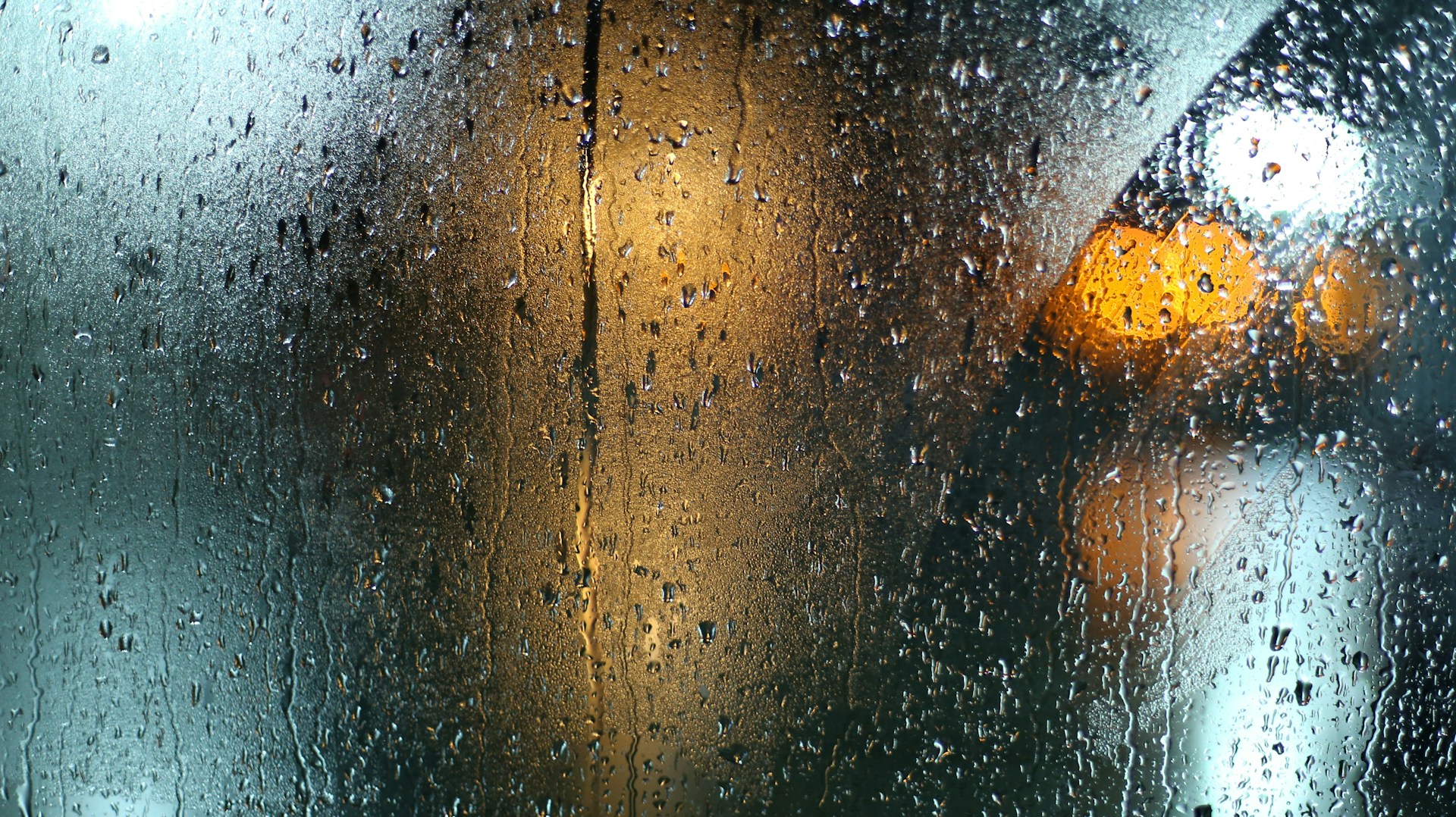 Rain-covered glass with blurred warm lights behind, signal obscured by noise