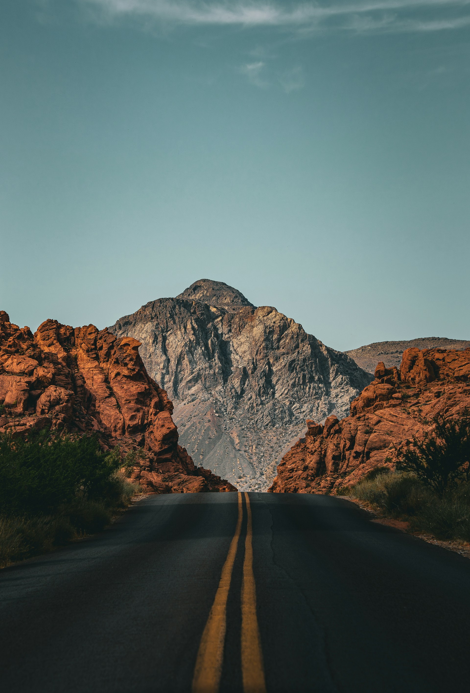 Desert road with guardrails leading toward red mountains in Valley of Fire, Nevada