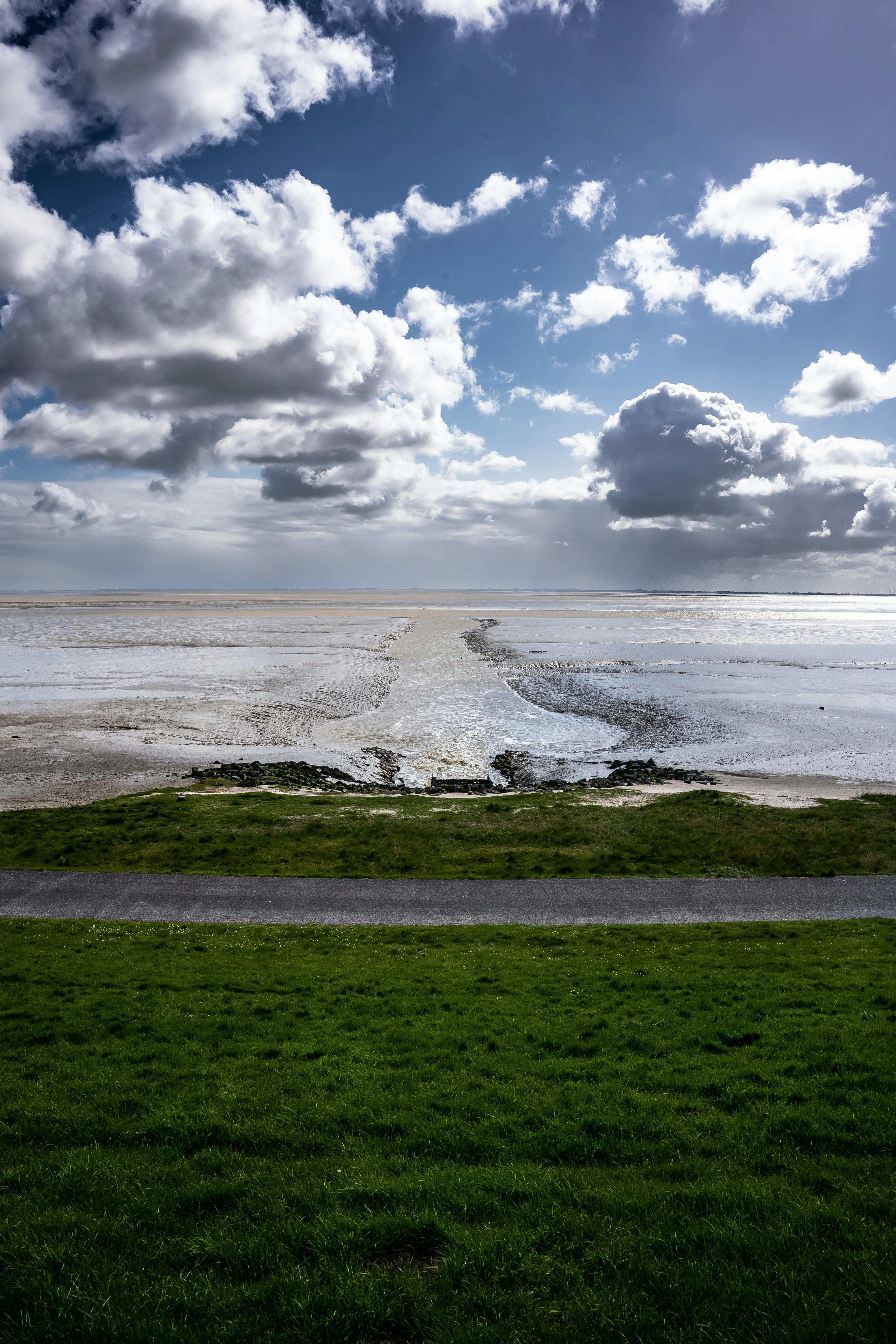 Coastal mudflat landscape under dramatic cloudy sky, visibility fading into the distance