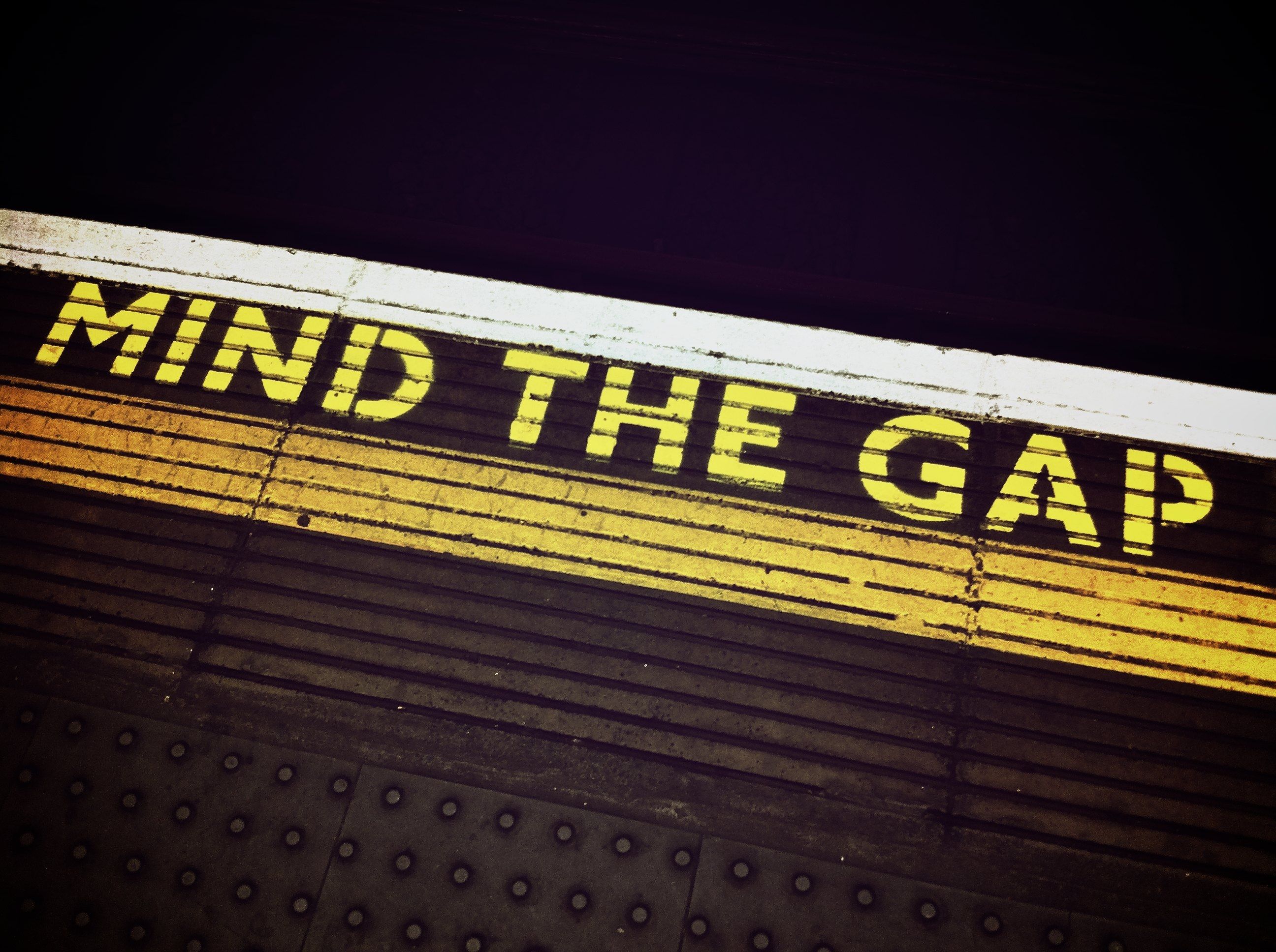 Mind the gap warning painted in yellow on a London Underground platform edge