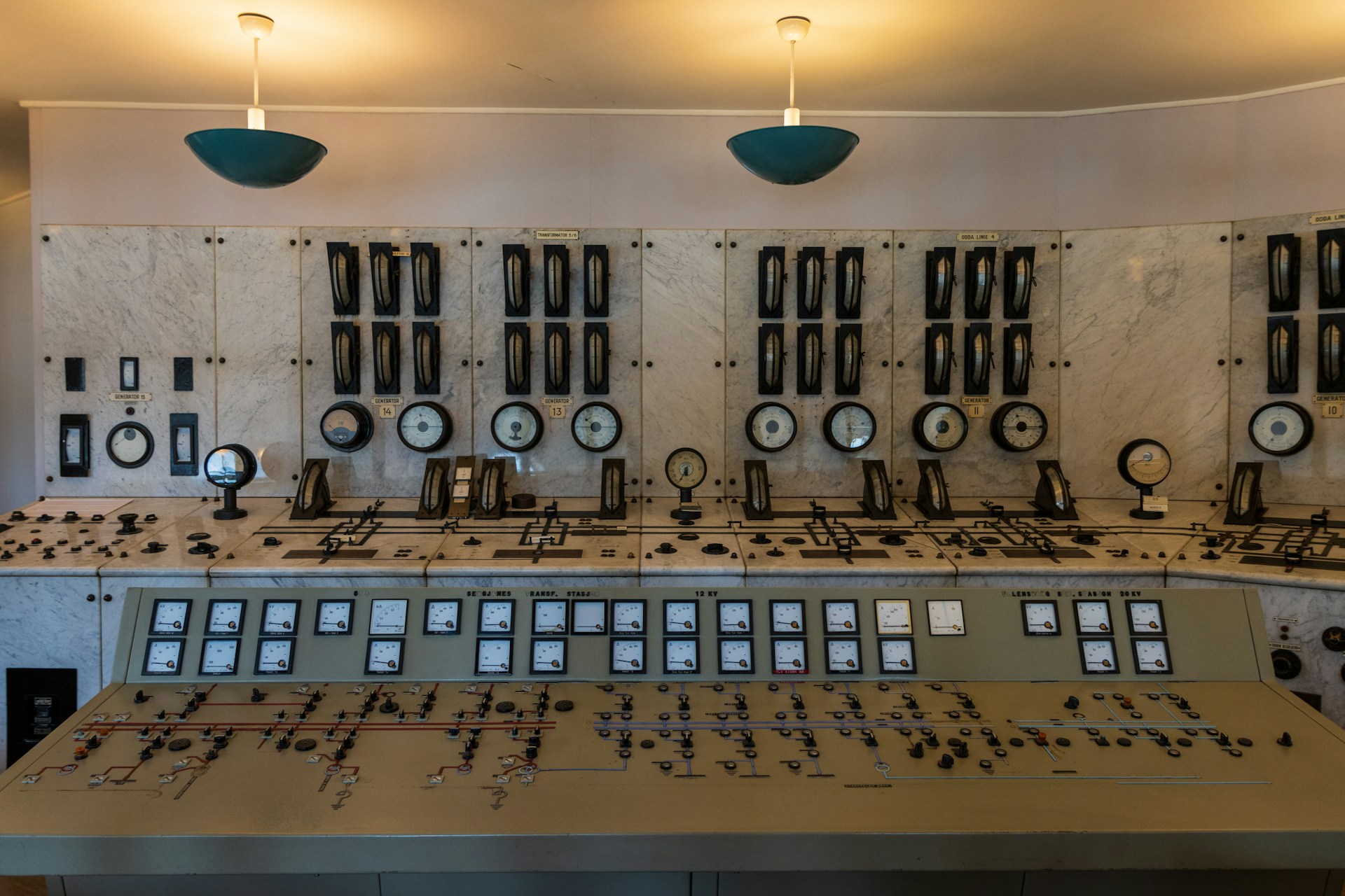 Vintage industrial control room with rows of analog gauges, dials, and switches on a marble panel
